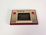 an image of a red and gold game console sitting on a white surface