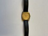 une montre en or posée sur un bracelet en cuir noir