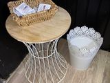 a small table with a basket on it next to a trash can