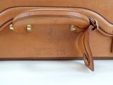 brown leather suitcase sitting on top of a white surface