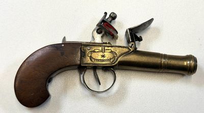 un vieux pistolet avec une poignée en bois sur une surface blanche