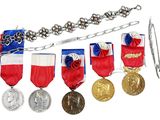 several medals and a chain are on display on a white surface