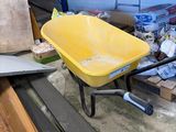 a yellow wheelbarrow sitting in a garage next to a pile of wood