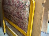 a bed with a yellow frame and a red and yellow cover
