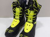 the pair of black and yellow snow boots are sitting on a white surface