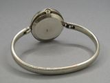 une photo en gros plan d'une bague en argent sur laquelle est posée une montre