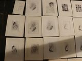 a lot of drawings on a table with a person standing next to them