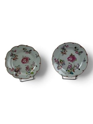 pair of porcelain plates with floral designs on them on a white surface