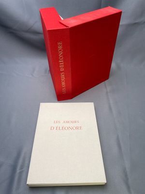 un livre ouvert posé sur une table, à côté d'une boîte rouge