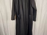 a black coat hanging on a hanger in front of a white curtain