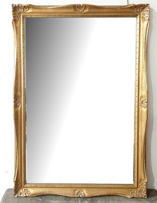 un miroir au cadre doré ouvragé posé sur une étagère en pierre