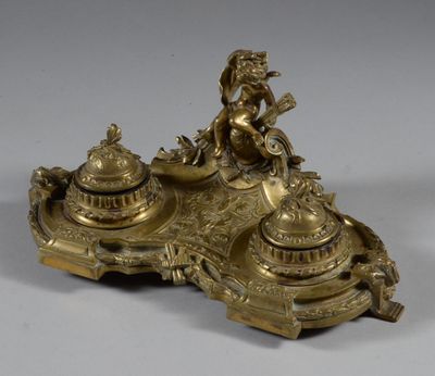 an antique brass inkwell with a woman sitting on top of it