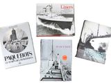 quatre livres posés sur une surface blanche, avec un bateau en arrière-plan