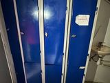 trois casiers bleus dans une salle de bains, à côté des toilettes