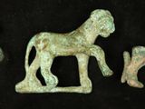 three bronze figurines of horses and a dog on a black background