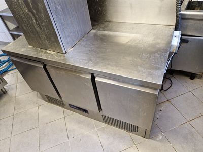 plan de travail en acier inoxydable dans une cuisine professionnelle, avec deux fours à l'arrière-plan