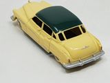 a yellow toy car with a green roof on a white surface