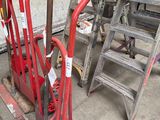 a red hand truck with a red handle next to a set of ladders