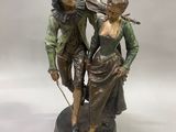 statue représentant un homme et une femme tenant un violon, posée sur un socle