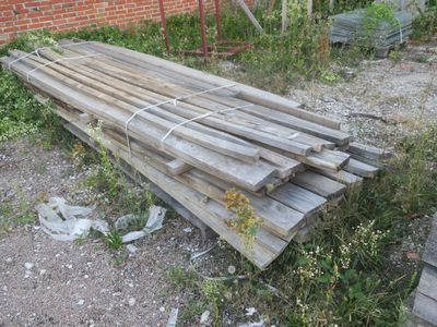 un tas de bois posé par terre devant un bâtiment en briques