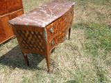 une commode au plateau en marbre posée dans l'herbe