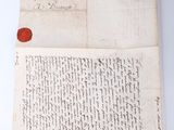 an old letter with a wax seal on it sitting next to a piece of paper