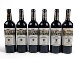 six bottles of wine are lined up in a row on a white surface