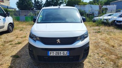 une petite camionnette blanche garée sur un parking à côté d'autres voitures