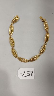 gros plan d'un bracelet en or sur une surface blanche