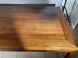a wooden table with a brown top on a tiled floor