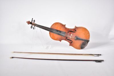 un vieux violon posé à côté d'un archet, sur une surface blanche