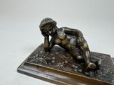 bronze statue of a baby lying on a wooden base