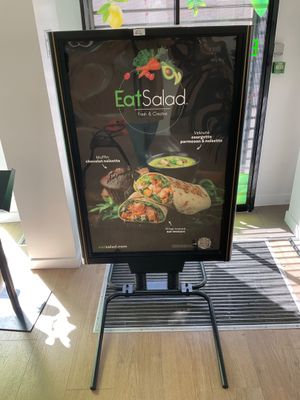 a sign that says eat salad on it in front of a window