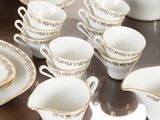 a lot of white and gold dishes and cups on the table