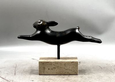 statue of a dog leaping on a marble base on a gray background