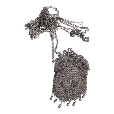 sac à main en métal argenté avec une chaîne qui l'entoure, sur fond blanc