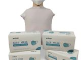 une personne portant un masque à côté de trois boîtes de masques jetables