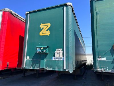 trois semi-remorques garées côte à côte sur un parking