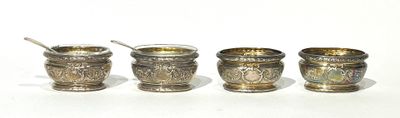 three silver cups with spoons in them on a white surface