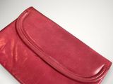 an image of a red leather clutch bag on a white background
