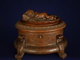 an antique bronze box with a baby in it on a stand