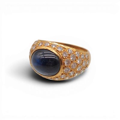 une image représentant une bague en or sertie d'une pierre bleue entourée de diamants blancs