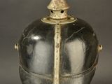 an antique silver and gold helmet on a clear stand