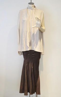 un mannequin vêtu d'une jupe et d'une veste, posé sur un socle
