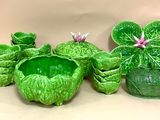 trois pots en céramique verts, ornés de fleurs et de feuilles, posés sur une table