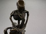 a bronze statue of a skeleton sitting on top of a table