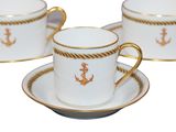 a cup and saucer set with a gold anchor on it