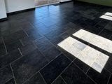 a black tile floor in an empty room with a sliding glass door