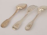 three forks and spoons sitting on top of a white table