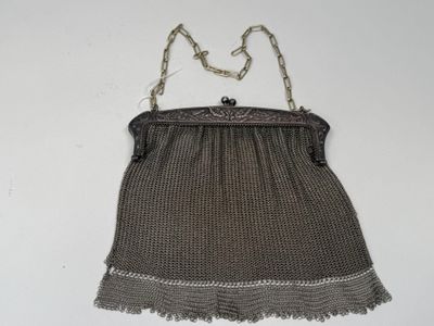 an old silver mesh purse hanging on a white wall